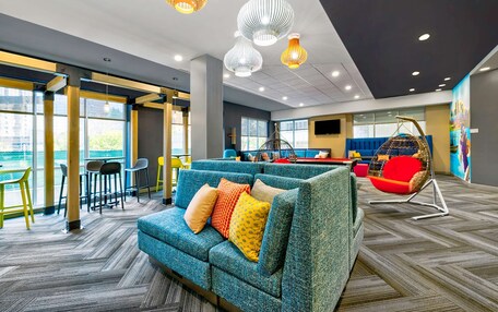 A modern lounge area with a blue sofa, colorful cushions, and a hanging chair.
