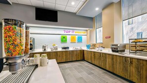Un área de desayuno moderna con mostrador, dispensador de cereales y un letrero que dice "TOP IT BREAKFAST".