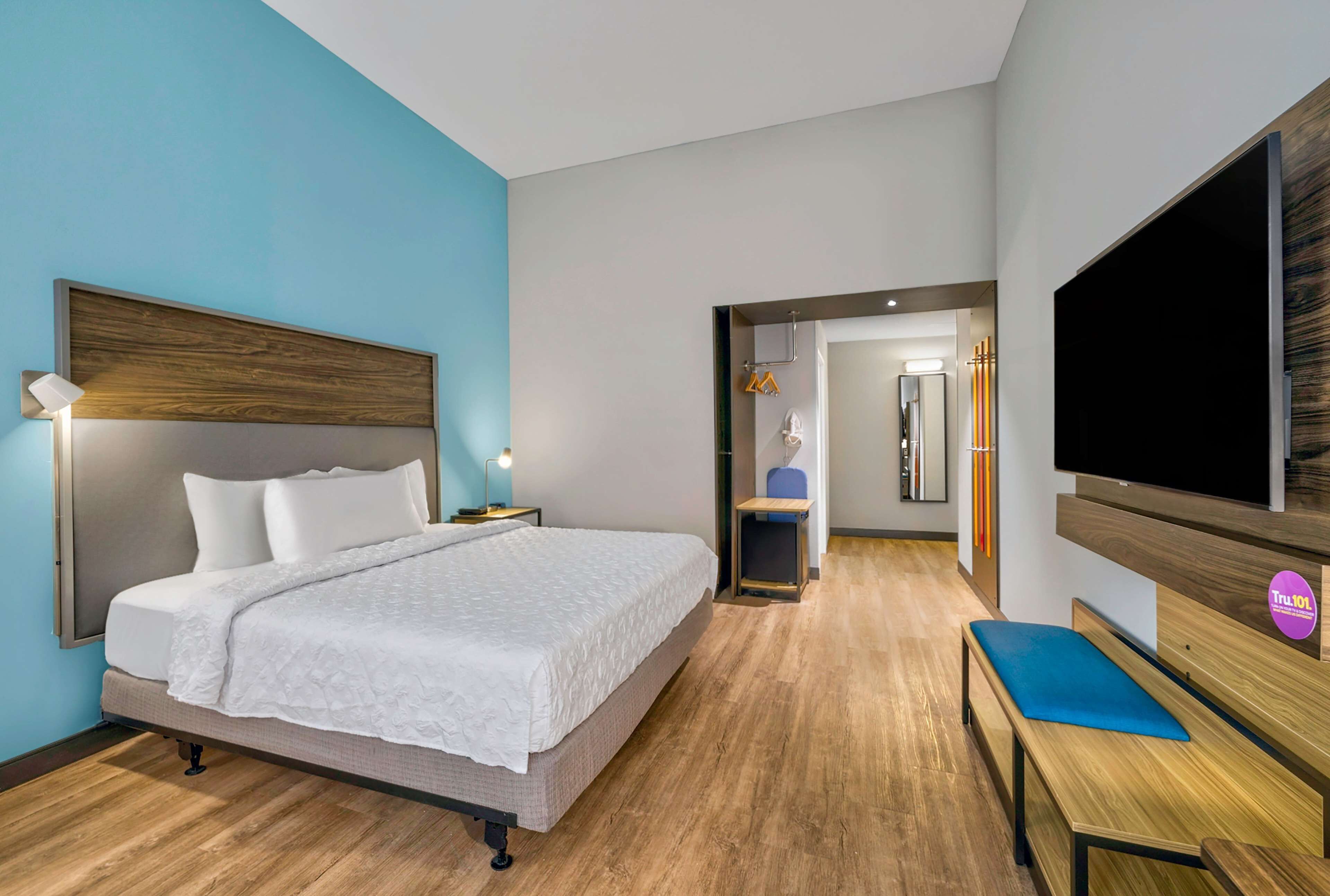 Une chambre d’hôtel avec un grand lit, un bureau, une télévision et un miroir.