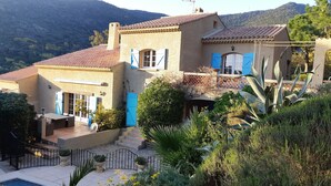 Une villa de style méditerranéen avec un toit en tuiles, un patio agrémenté de mobilier d’extérieur et une piscine.