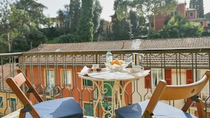 Un balcone con un tavolo apparecchiato per la colazione, inclusi pane, una bottiglia e una tazza.