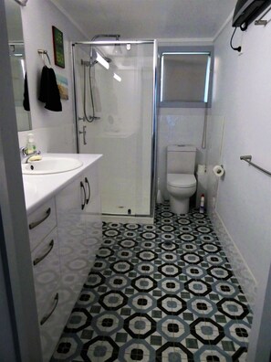 A bathroom with a white sink, a glass shower enclosure, a toilet, and patterned floor tiles. - Eagles Nest Cottage where everything is better with an ocean view and breeze (Crowdy Head)