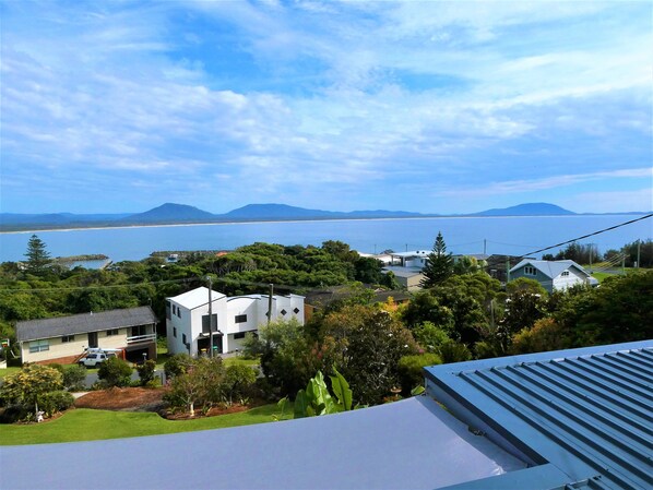 A residential area with houses, a beach, and mountains in the distance. - Eagles Nest Cottage where everything is better with an ocean view and breeze (Crowdy Head)