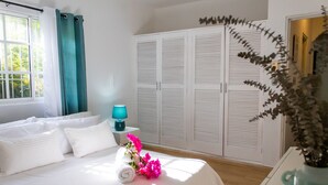 A neatly made bed with pillows and a rolled towel, a bedside lamp, and a vase with flowers. - Beauty Bavaro Playa Matilde (Punta Cana)