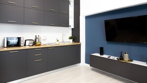 A modern kitchen with dark cabinets, a wooden countertop, a microwave, a toaster, and a sink. - Metropole Apartments Old Center (Bucharest)