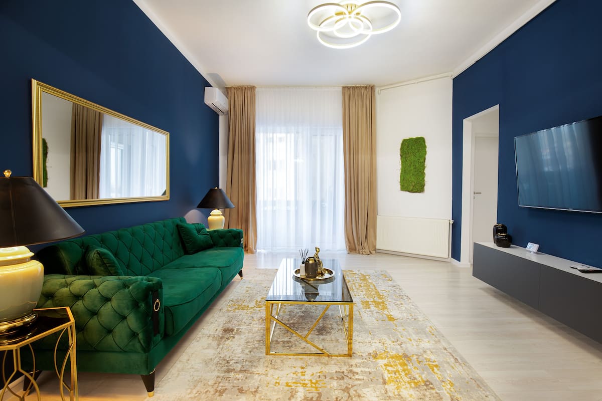 A modern living room with a green sofa, a glass coffee table, and a large mirror.
