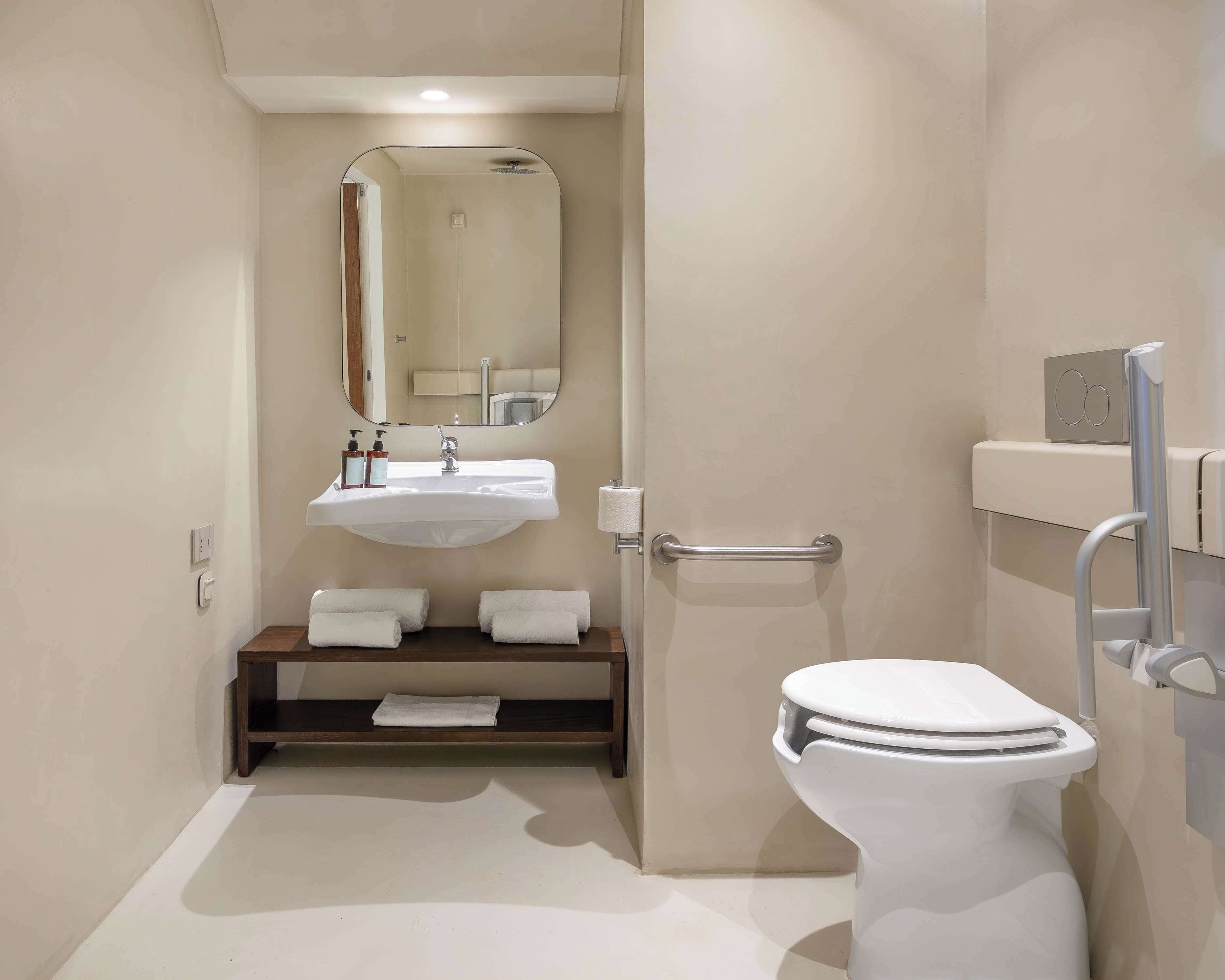 Een moderne badkamer met een witte wastafel, spiegel en toilet.
