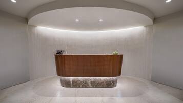 A reception desk with a marble base, recessed lighting, and a curved ceiling.