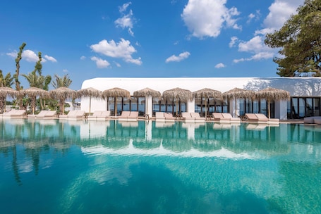 Outdoor pool, pool loungers. Isla Brown Corinthia Resort & Spa, Curio Collection Hilton