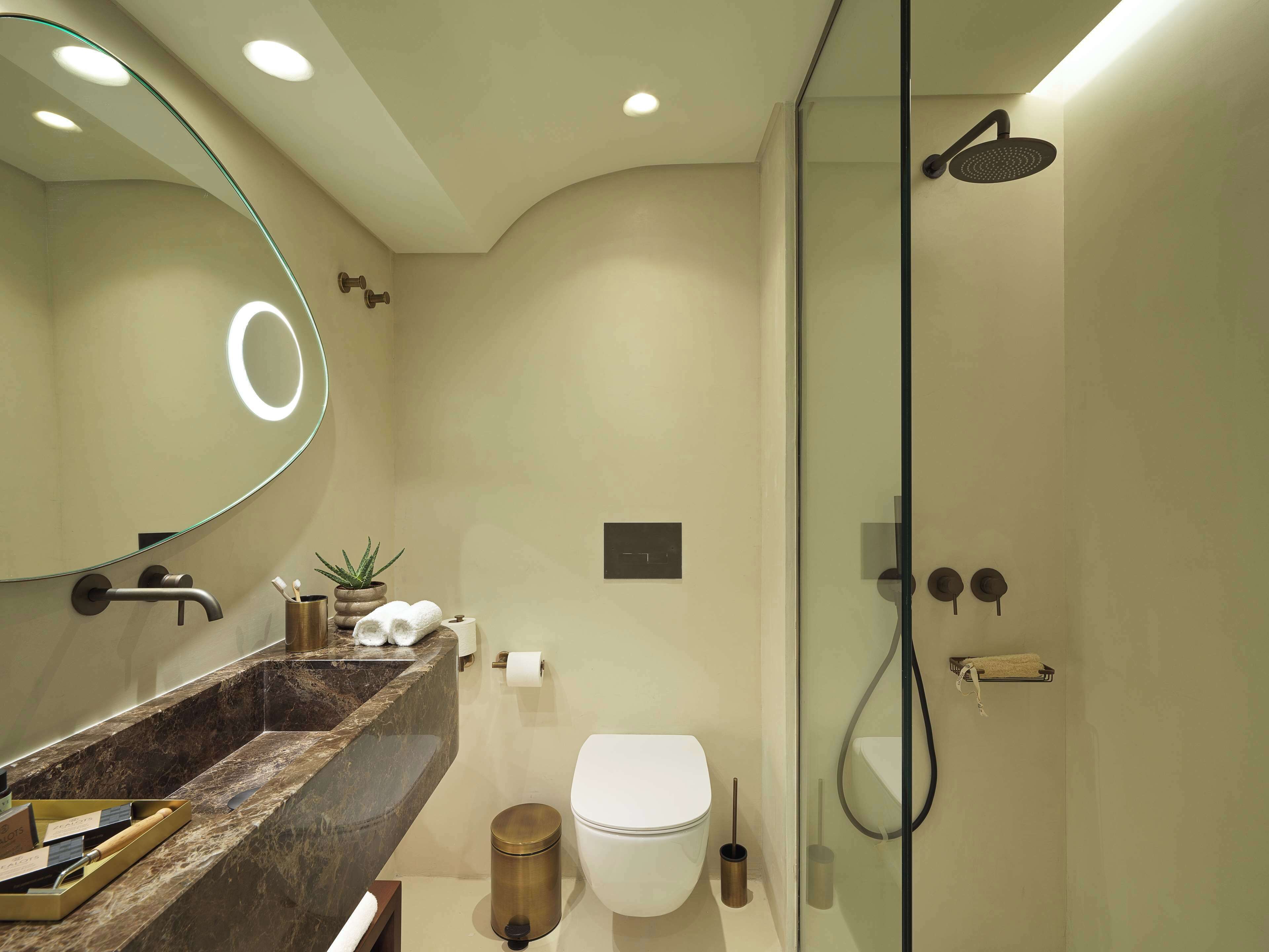 A modern bathroom with a glass-enclosed shower, a marble sink, and a toilet.