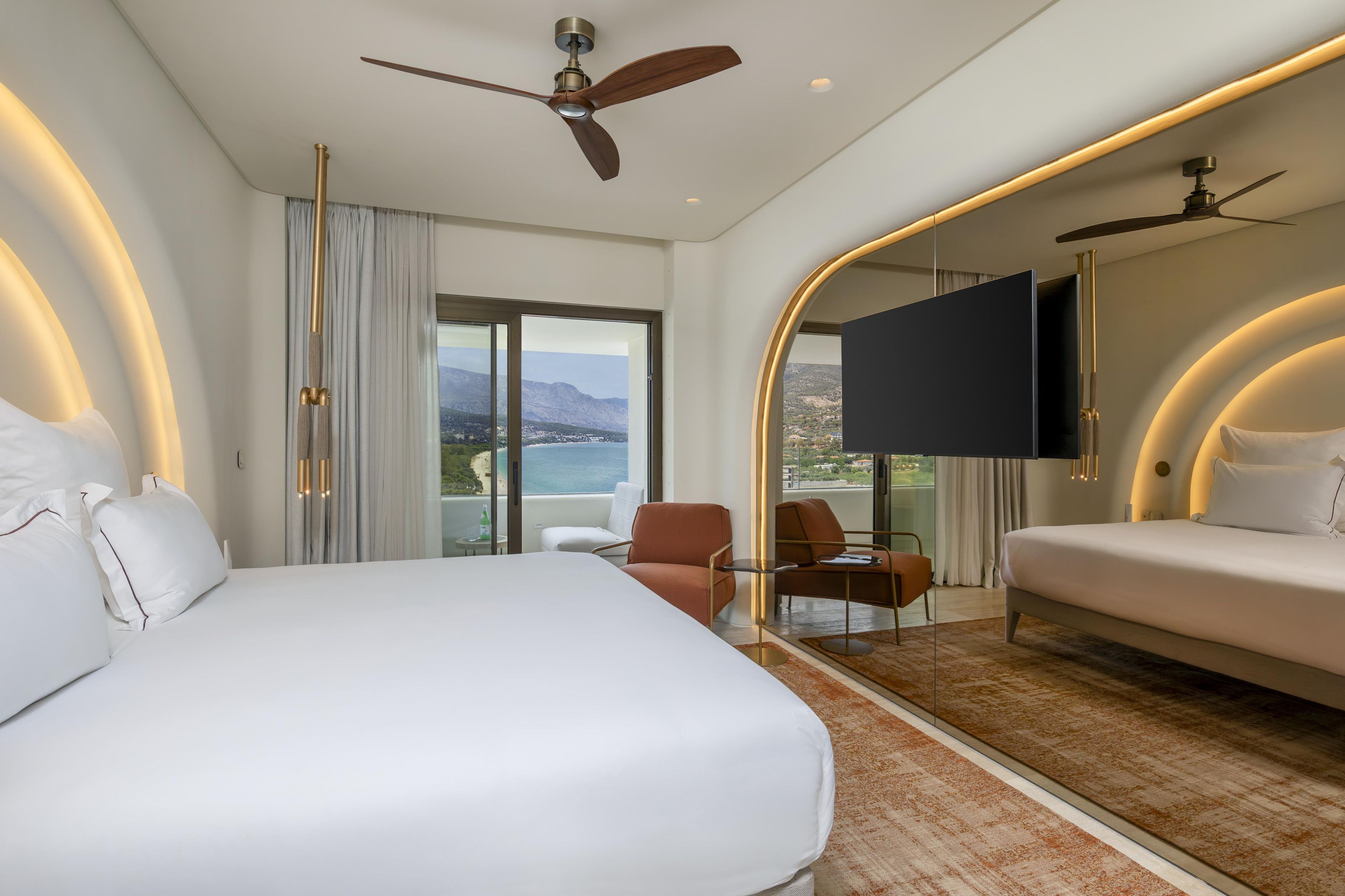 Habitación de hotel con una cama grande, un sofá, un televisor y un balcón con vistas.
