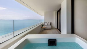 Een balkon met uitzicht op zee, een bank, een tafeltje en een jacuzzi.
