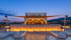 Een dakterras met modern design, met een bar en een zithoek met lounge fauteuils en tafels.