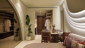 A modern hotel room with a large bed, a dining area, and a walk-in closet.