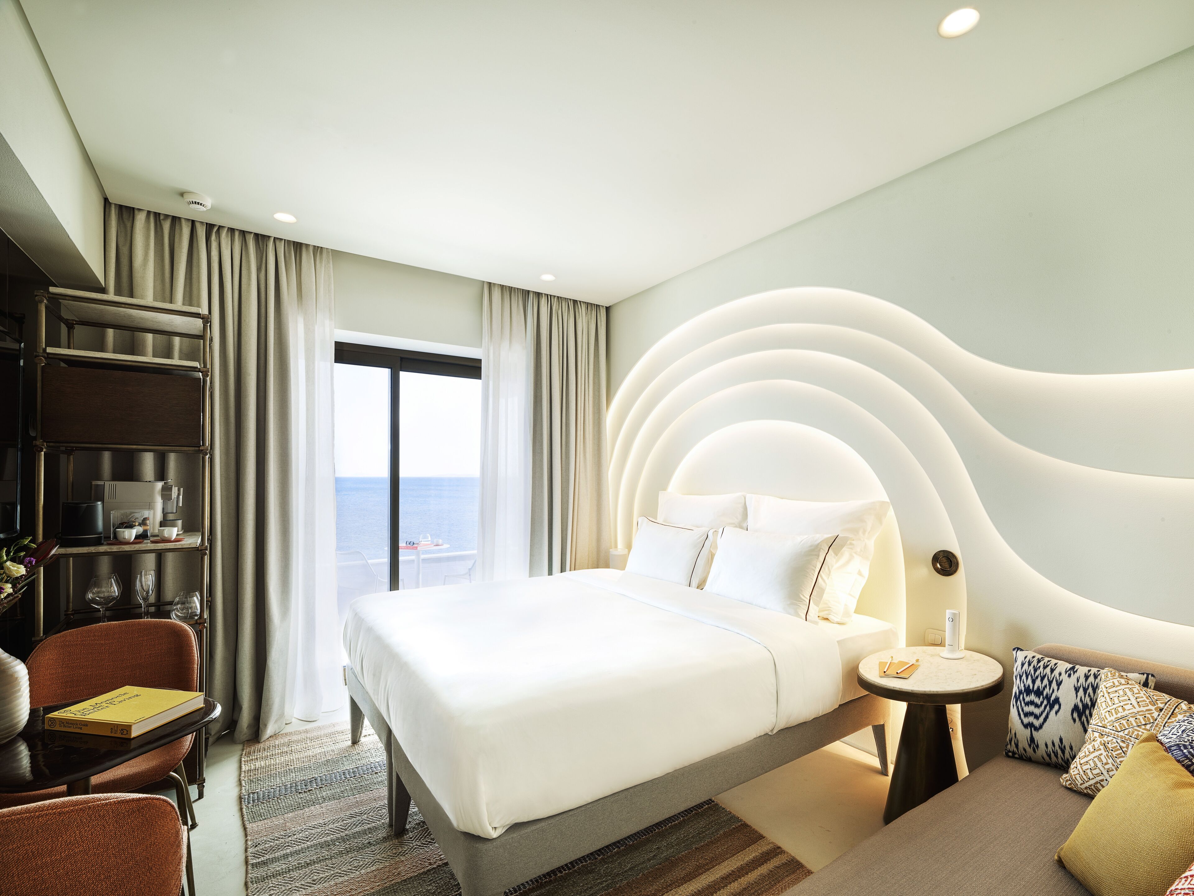 Une chambre d’hôtel moderne avec un grand lit, un bureau et une vue sur la mer.
