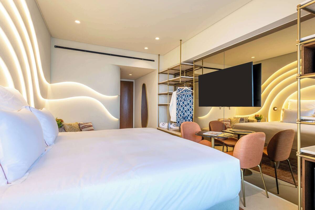 Une chambre d’hôtel moderne avec un grand lit, un bureau et une télévision.