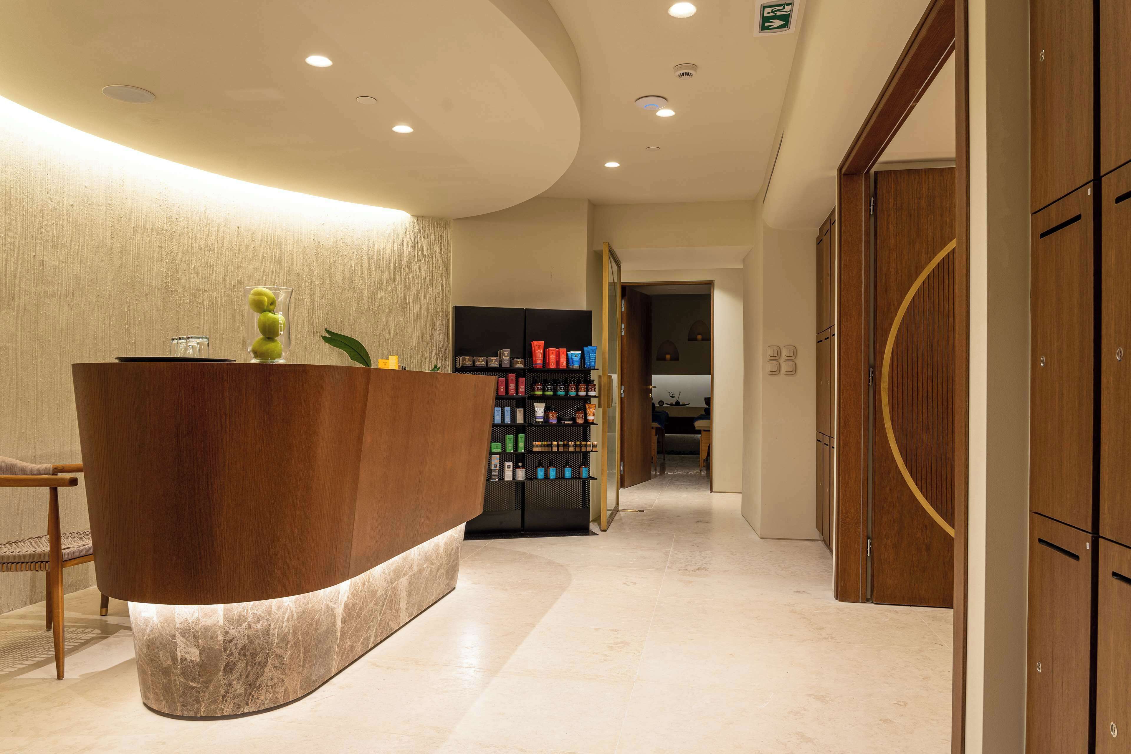 Zona de recepción con un mostrador de madera, una vitrina con objetos decorativos y una estantería con varios productos.
