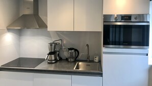 Een moderne keuken met roestvrijstalen apparatuur, een inbouwoven en een koffiezetapparaat.