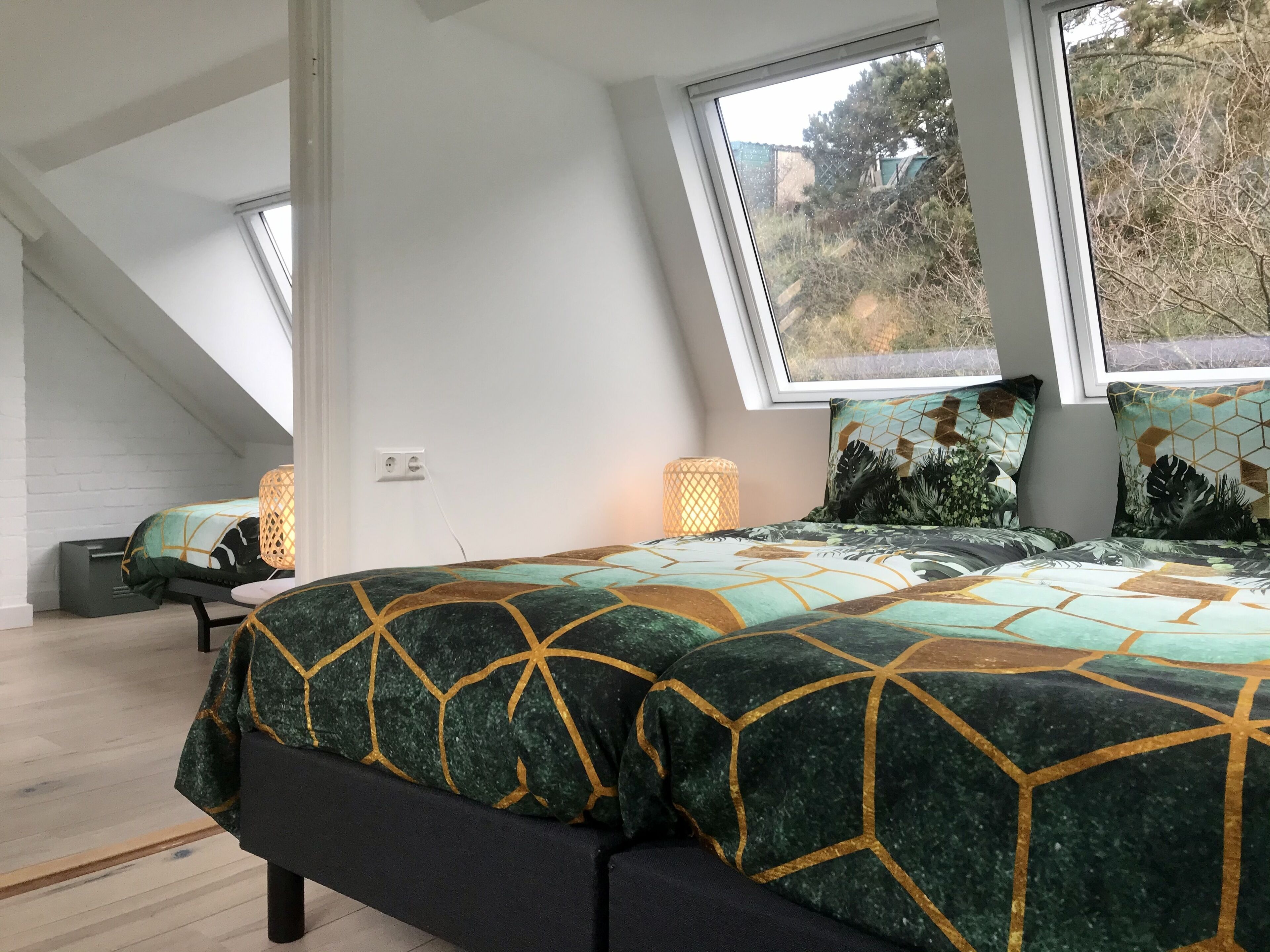 Une chambre avec un grand lit, une fenêtre et un petit coin salon.