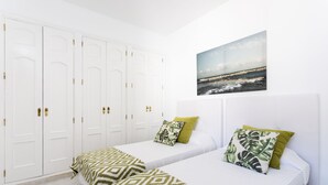 Ett hotellrum med två sängar, en stor garderob och en tavla som föreställer en strandvy.