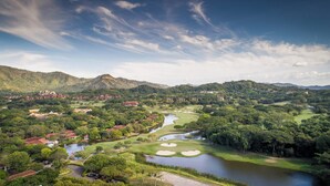 A golf course with multiple bunkers, a river, and surrounding greenery. - Villa Zindagi (Cabo Velas)