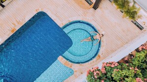 A rooftop pool with a tiled edge and a person lying on the edge.