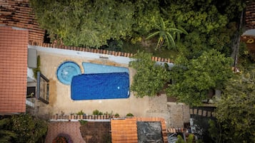 Vista aérea de una zona de piscina en la azotea, con una piscina rectangular grande, una piscina circular más pequeña y vegetación circundante.