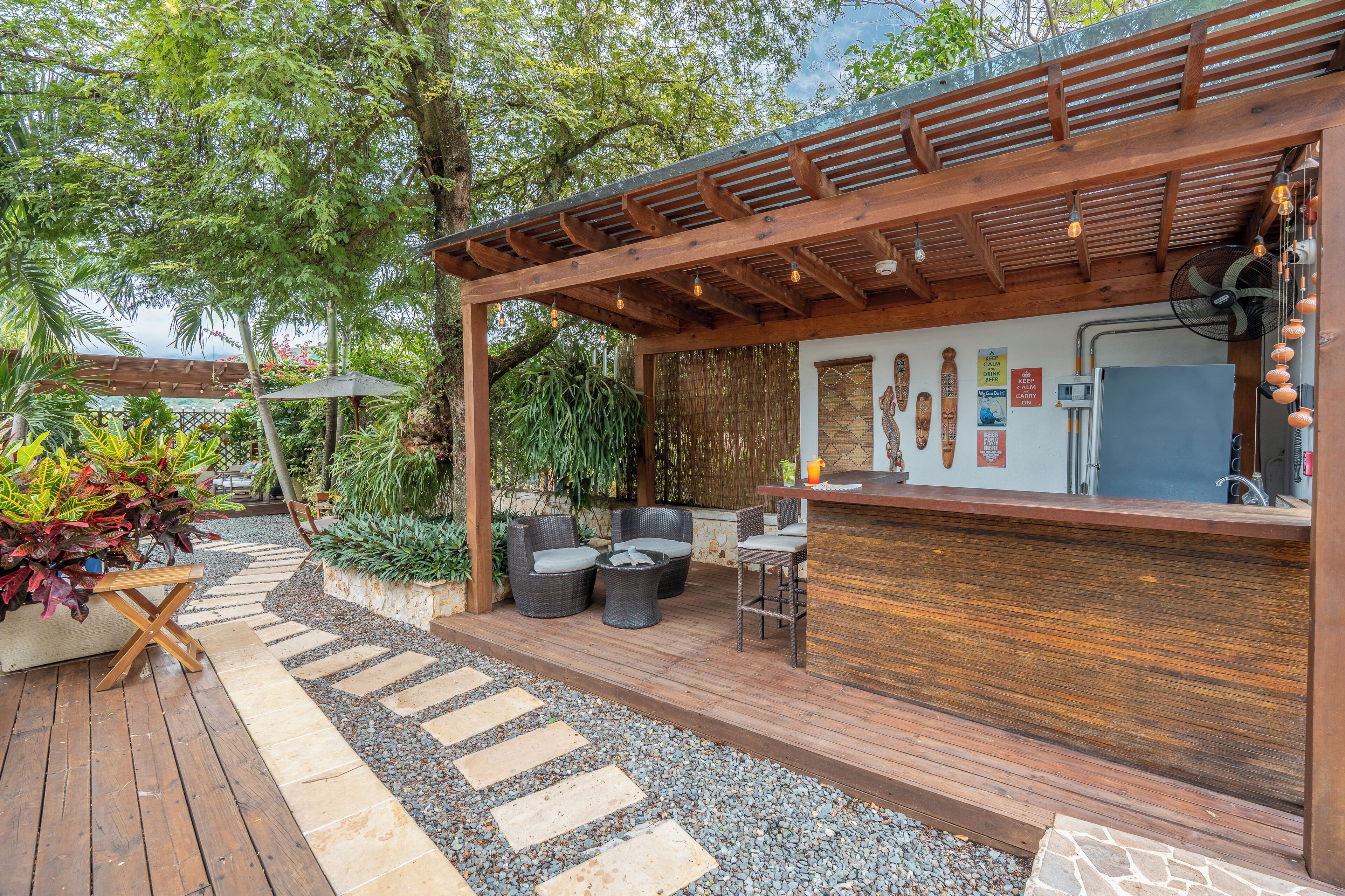 Un espace bar extérieur doté d’un plancher en bois, de sièges et d’une pergola.