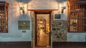 A hotel entrance with a stone facade, wooden beams, and lanterns.