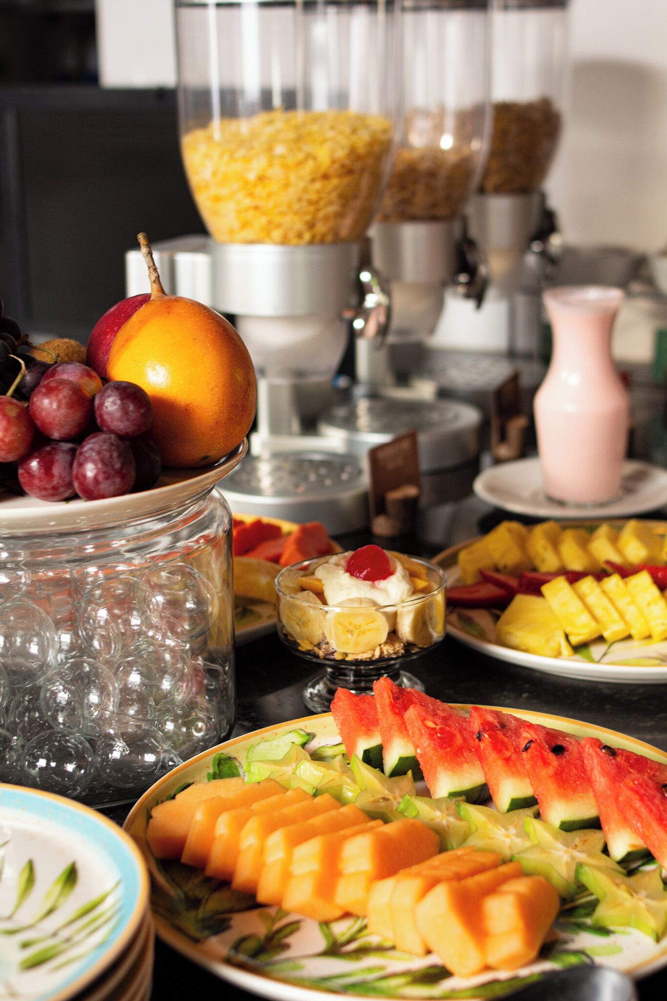 A buffet table with various fruits and a beverage dispenser.