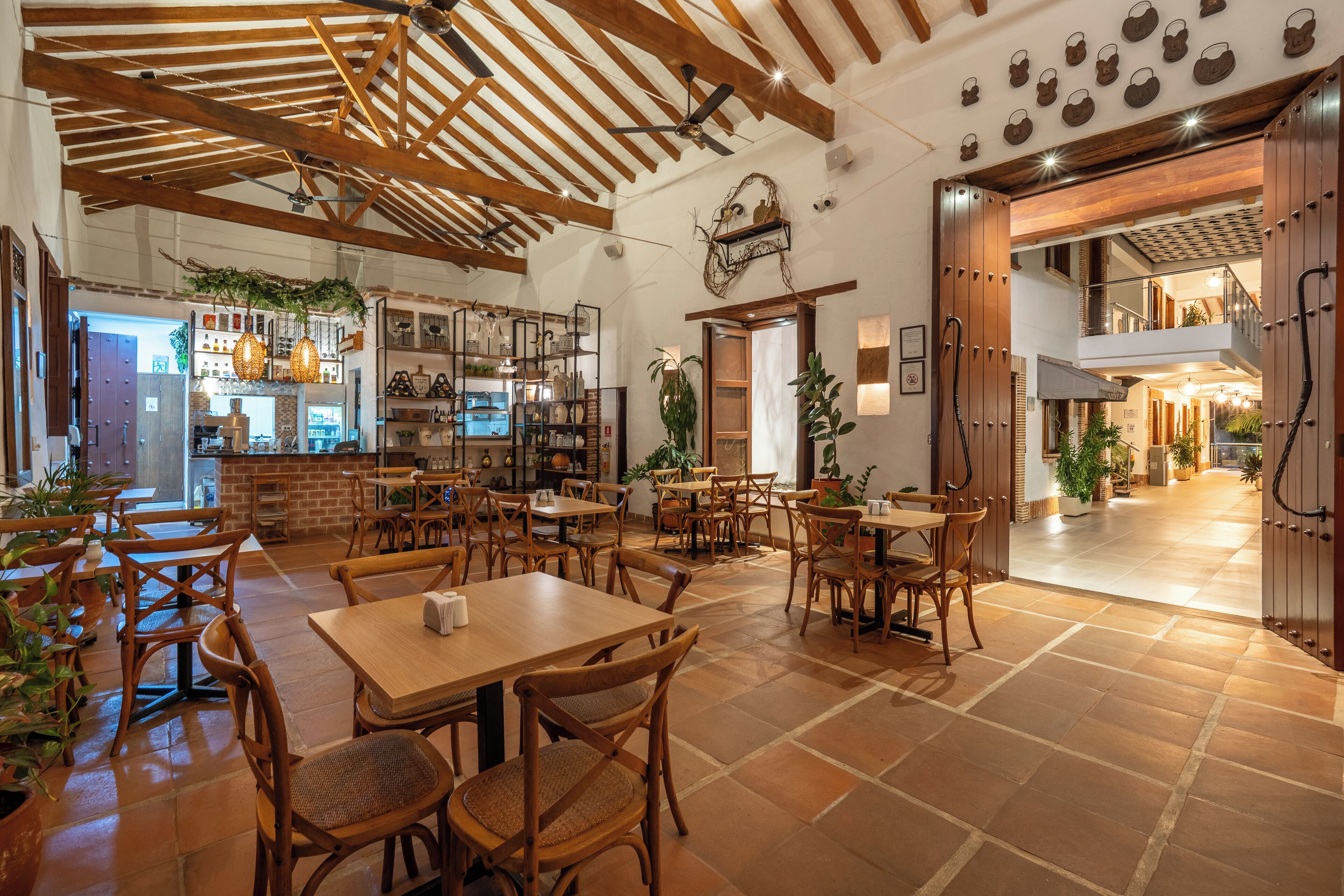 Un restaurant spacieux avec des tables et des chaises en bois, un espace cuisine et un escalier menant à un niveau supérieur.