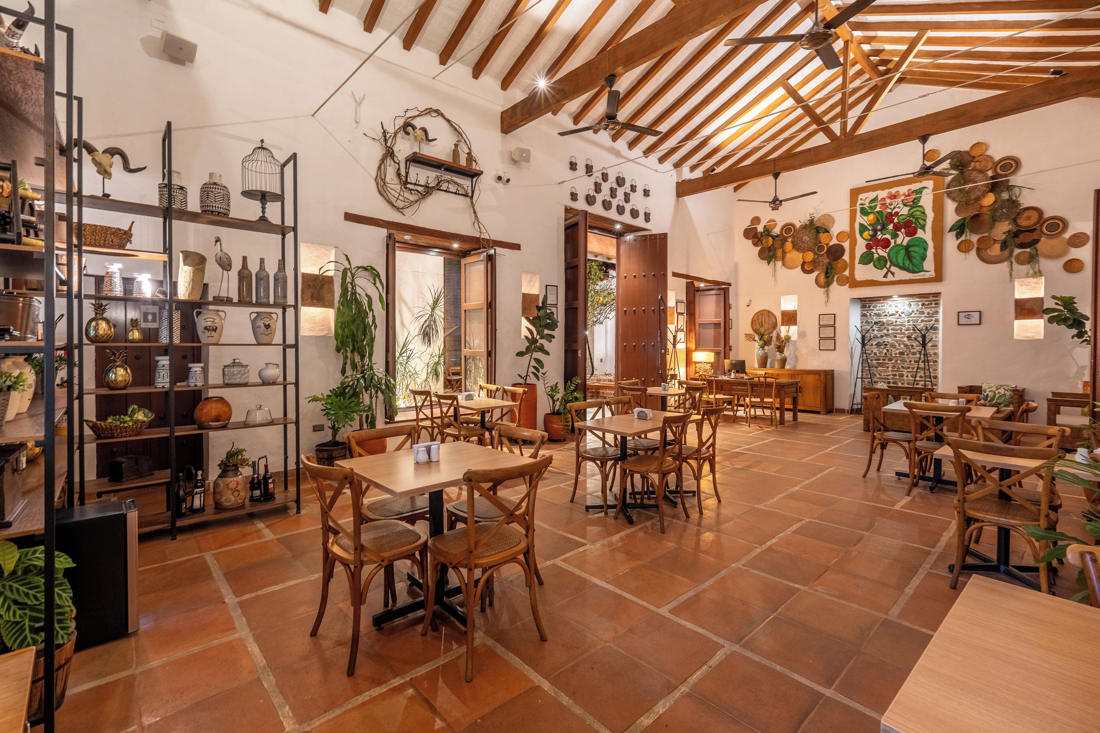 A spacious café with wooden tables and chairs, shelves with various items, and a rustic ceiling.