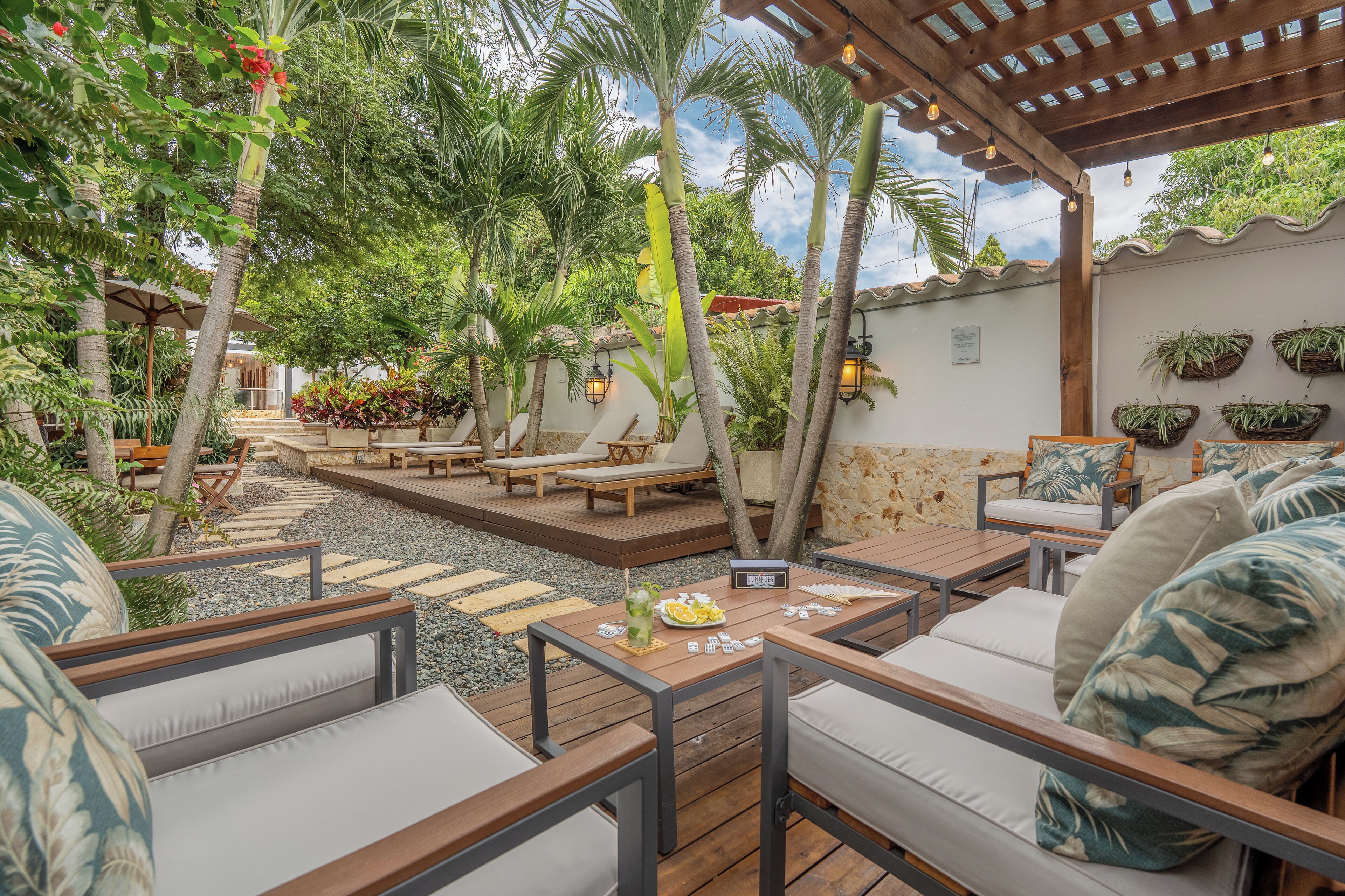 An outdoor patio with wooden furniture, a stone pathway, and lush greenery.