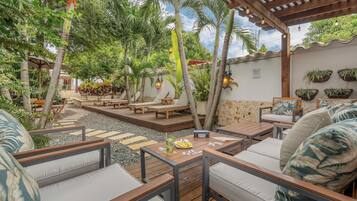 An outdoor patio with wooden furniture, a stone pathway, and lush greenery.