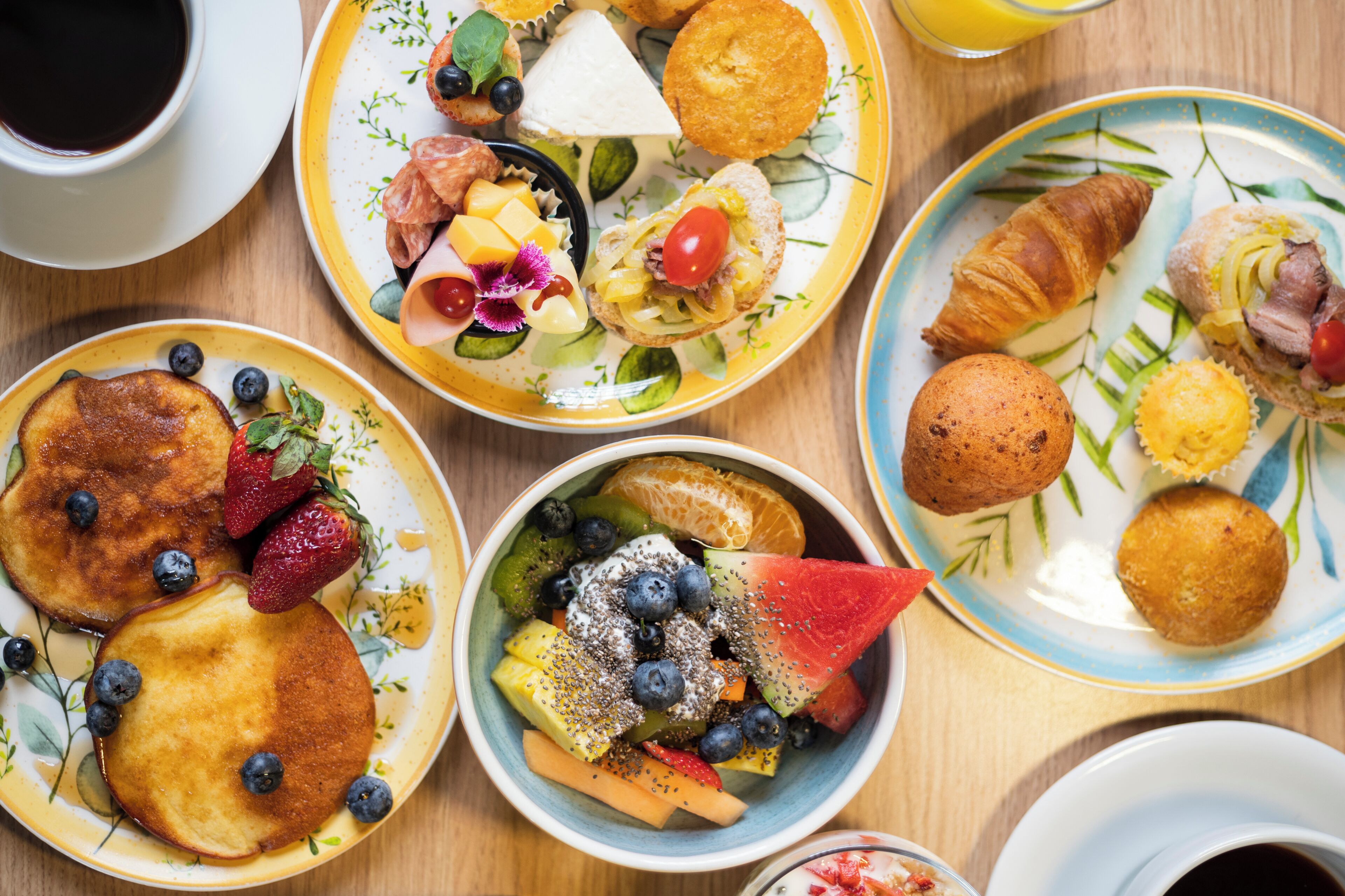 A breakfast setting with pancakes, croissants, and various fruit and cheese platters.