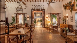A spacious dining area with wooden tables and chairs, a central open space, and a ceiling fan.