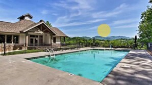 Uma área de piscina com uma casa ao fundo, rodeada por vegetação e montanhas.