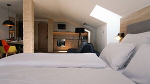 Ein Schlafzimmer mit einem großen Bett, einem Oberlicht, einer Essecke und einer Küche.