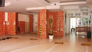 Un hall d’entrée spacieux, doté d’un sol carrelé, d’une plante en pot et d’un banc.