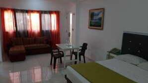 Une chambre d’hôtel avec un lit, un canapé, une table à manger avec des chaises et un tableau au mur.