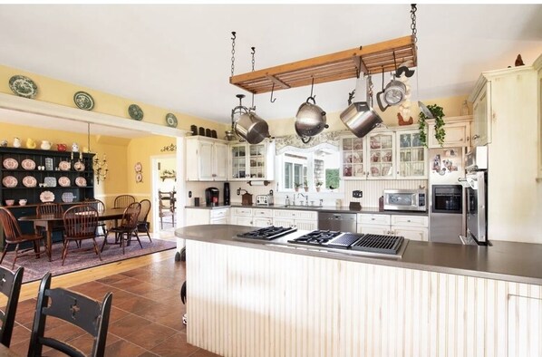 Enjoy cooking in this well-equipped kitchen with a central island, gas stove, microwave, and oven, surrounded by white cabinetry and a dining area.