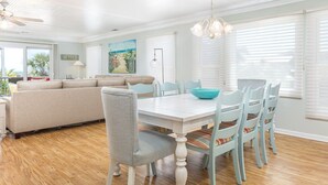 Un salón espacioso con un sofá grande, una mesa de comedor con sillas y un ventilador de techo.