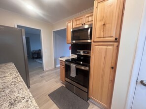 A modern kitchen with wooden cabinets, stainless steel appliances, and a granite countertop. - Little Bass Cabin - Kayaks & Clear Water Swimming (Grand Rapids)