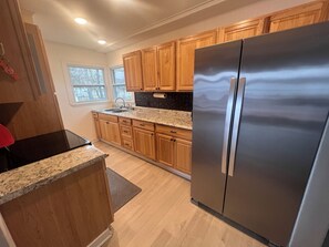 Una cocina con armarios de madera, un refrigerador de acero inoxidable y una encimera de granito.