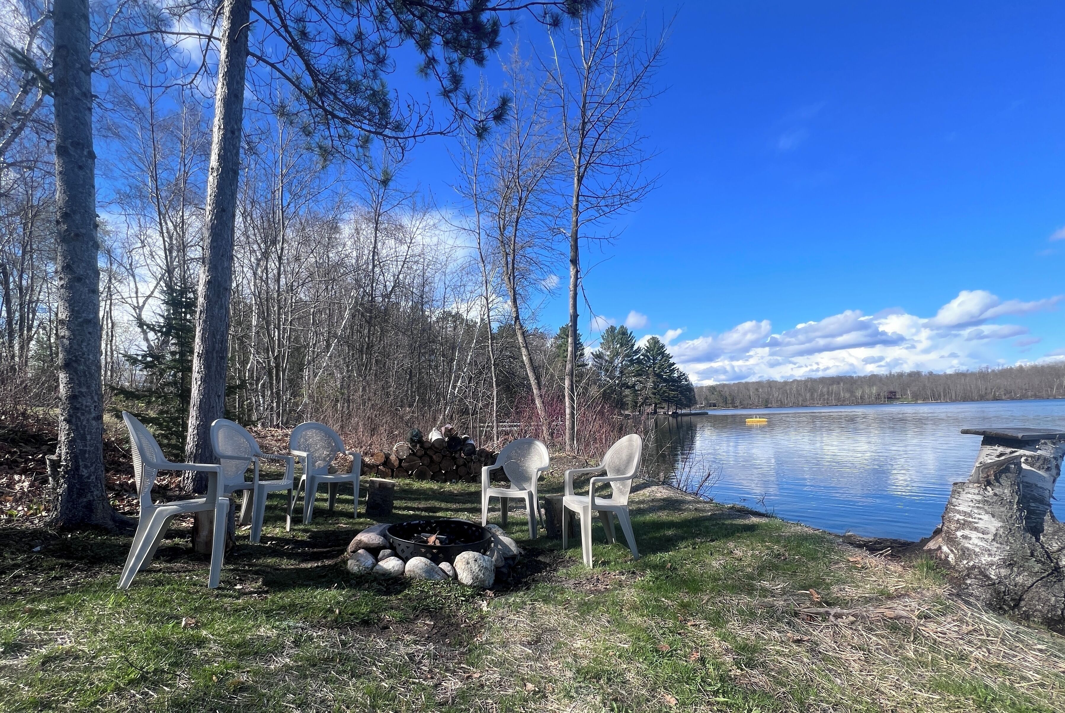 Un cadre idyllique au bord du lac, avec un foyer et des chaises blanches.