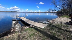 A calm lake with a dock, grassy area, and trees. - Little Bass Cabin - Kayaks & Clear Water Swimming (Grand Rapids)