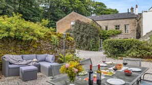 Relax in a serene garden setting with a wicker sofa and dining table.