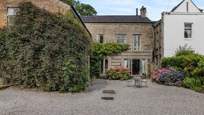 Stroll through the serene surroundings of this charming building, featuring a symmetrical facade and lush greenery.