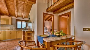 Uma área de refeições com uma mesa de madeira, cadeiras e vista para a cozinha.