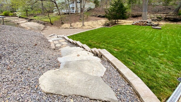 A well-maintained lawn with a stone pathway leading to a house surrounded by trees. - Beach Access to Ozark, Visit the Cottage on Valley Road! (Osage Beach)